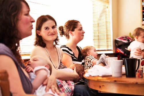 Mothers and their babies sit around a dining table at a Cuidiu coffee morning.